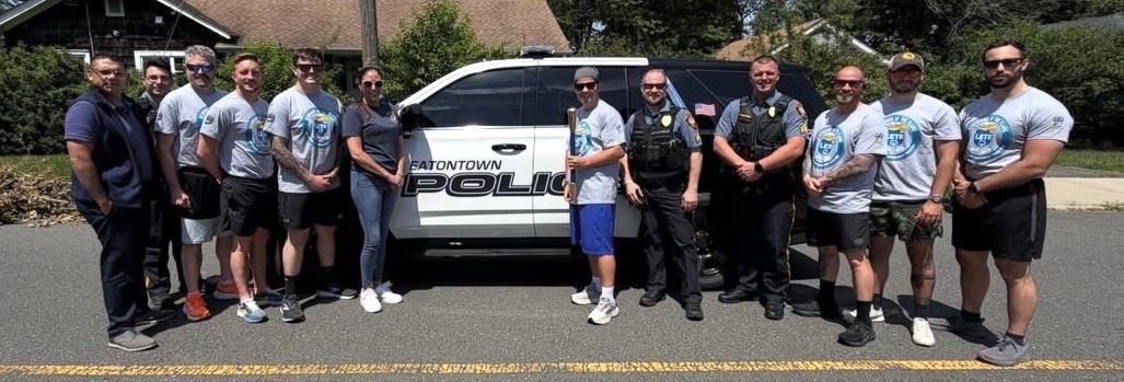 Group of men posing in front of an Eaton Township Police SUV on a street.